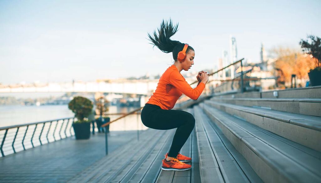 woman exercise outside in urban environment doing squat jumps