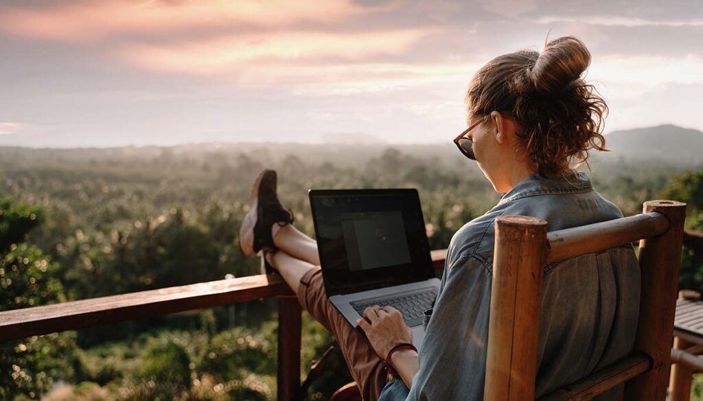 woman working on her computer outside over looking scenic valley