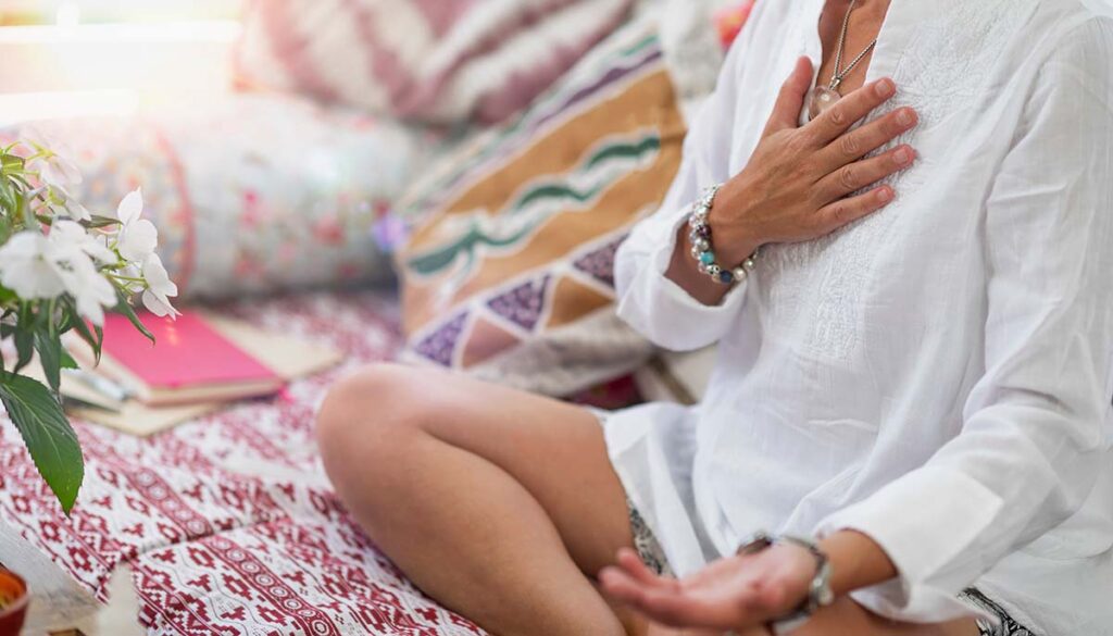 woman doing self healing heart chakra meditation in lotus position