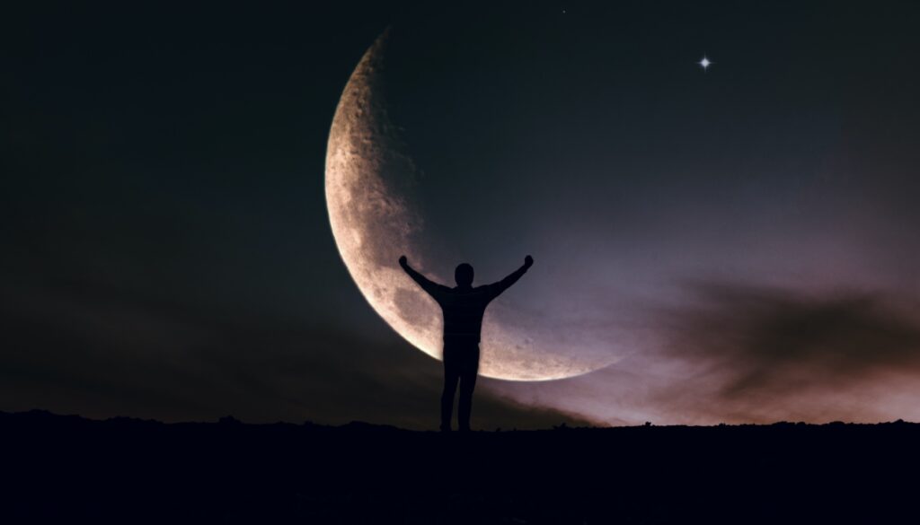 person with arms outstretch in front of a new moon