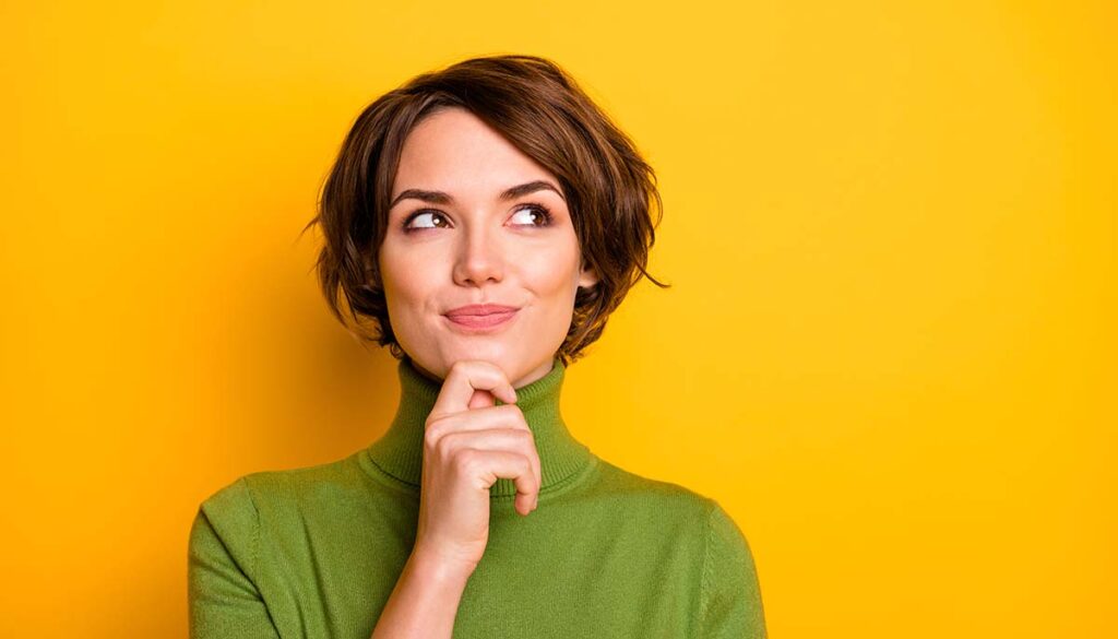 close up of woman against yellow background pondering happy thoughts