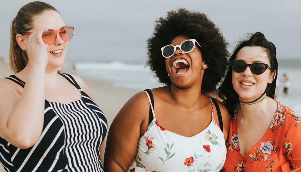 three female friends laughing together on the beach