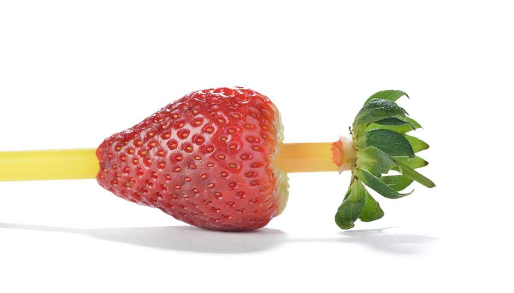 removing the stem from a strawberry with a straw