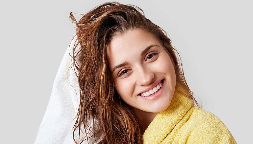 smiling woman towel drying hair after washing it