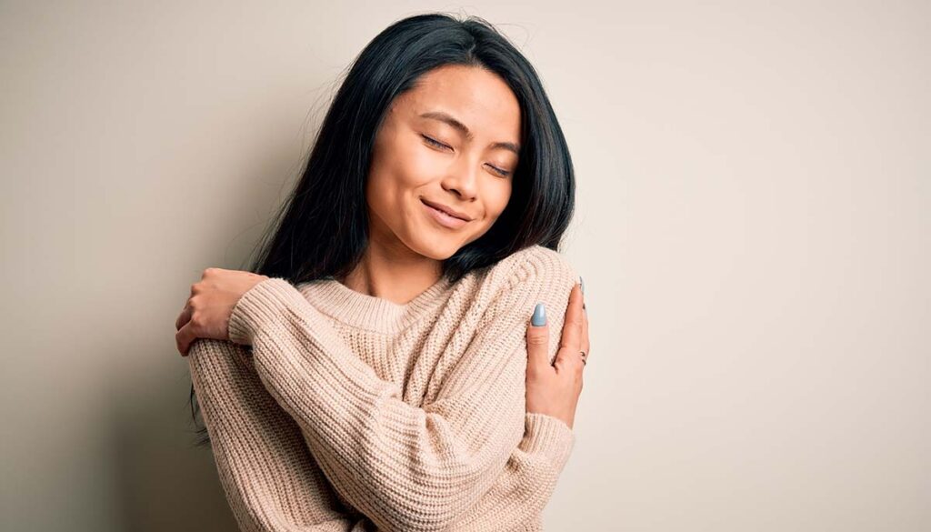 woman hugging herself on neutral background