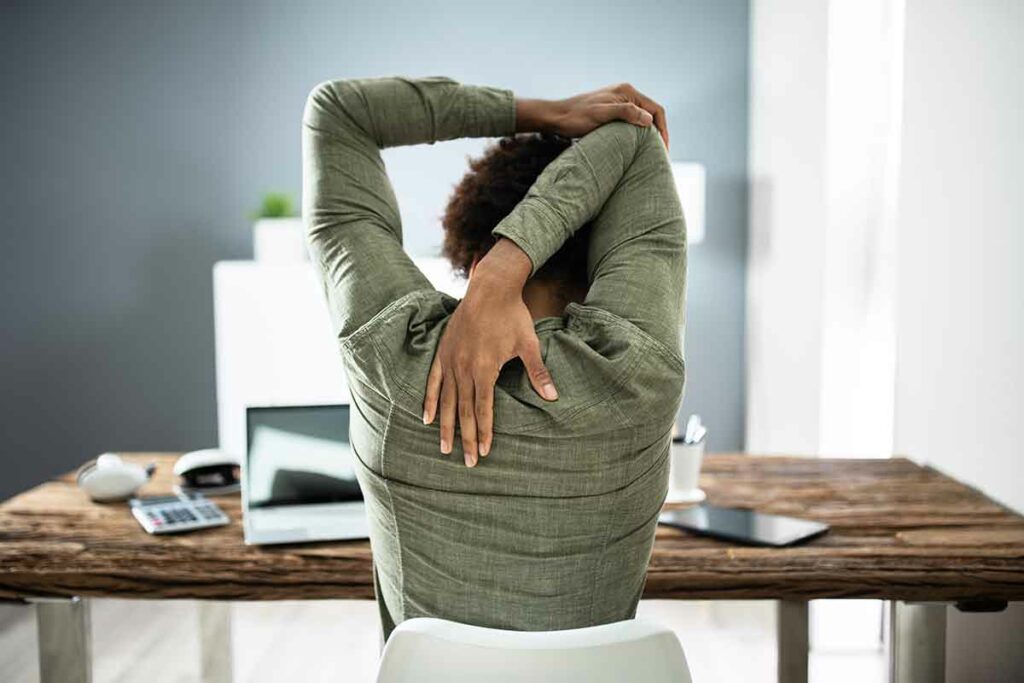 person stretching triceps at desk
