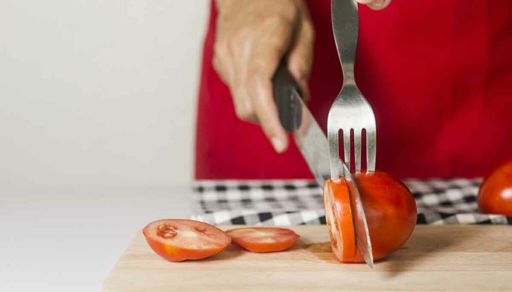 using a fork to help slice tomato