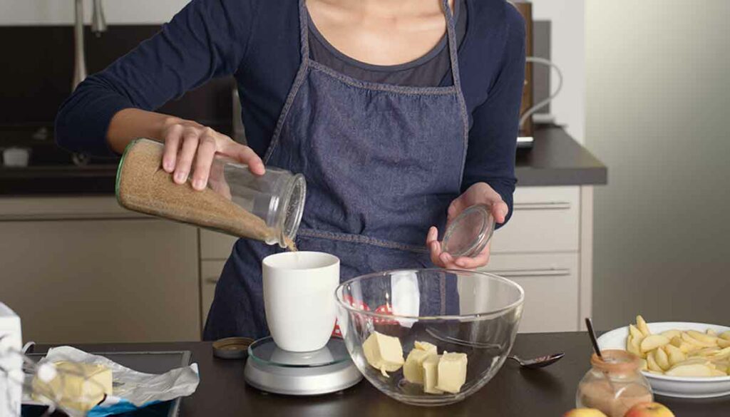 woman in the kitchen cooking, measuring ingredients with kitchen scale