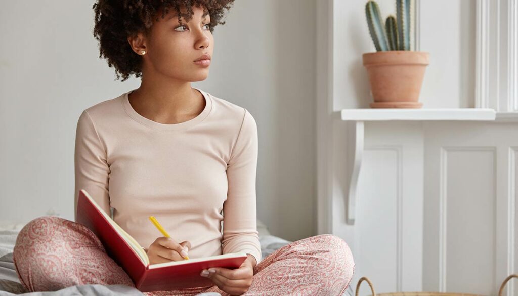 woman sitting and writing in a book or journal