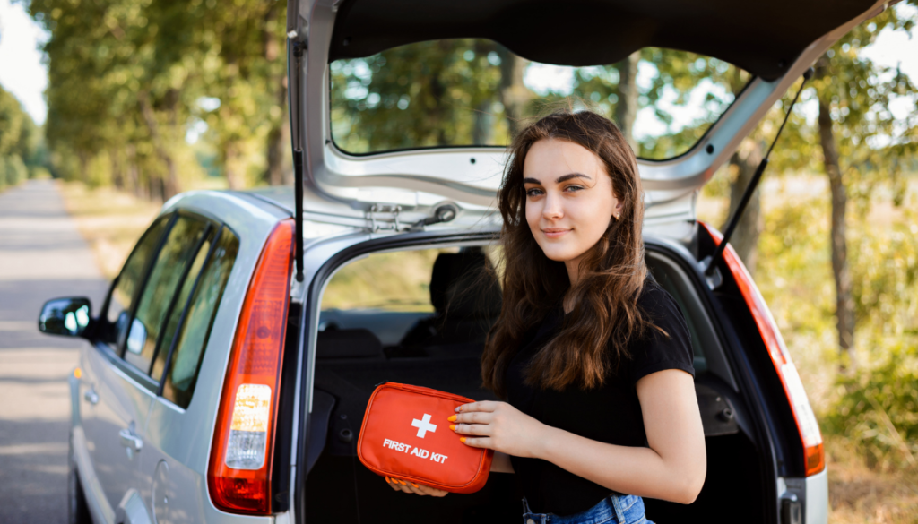Young woman taking first aid kit out of trunk