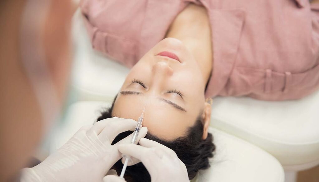 woman getting botox injection between the eyes