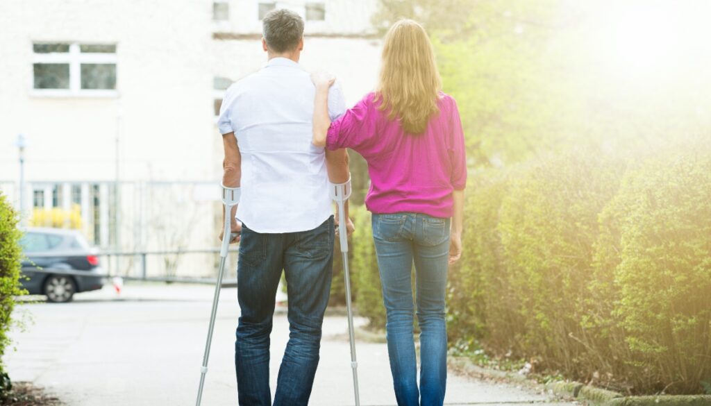 A woman helping a man on crutches