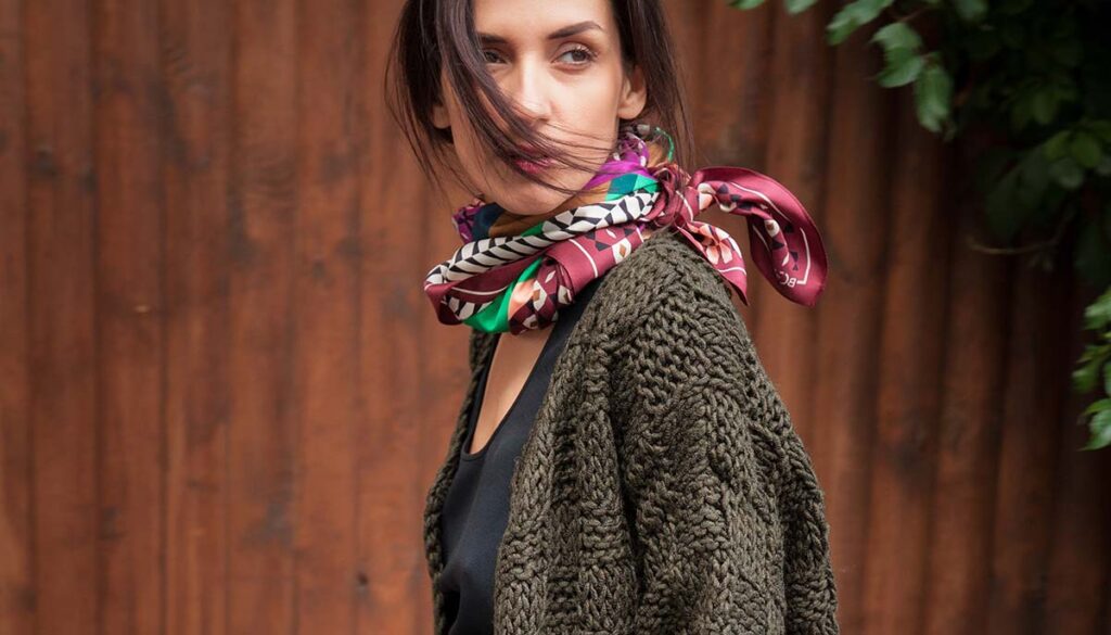 street style portrait of woman in muted crochet sweater and colorful neck scarf 