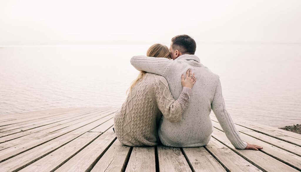 couple with their arm around one another on a dock