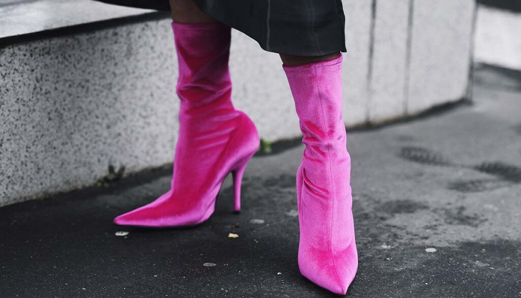 hot pink velvet high heel boots popping out beneath black outfit