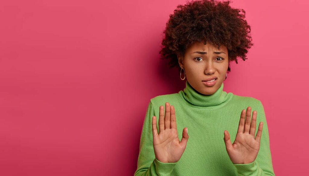 woman in bright green turtle neck on pink wall saying no in an awkward conversation