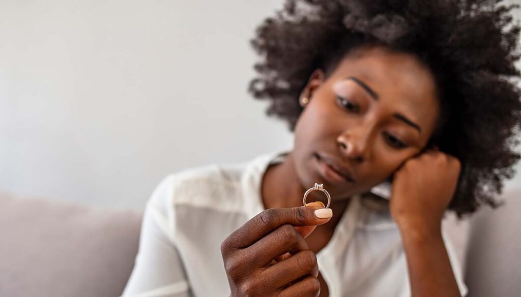 woman looking at engagement ring having doubts about marriage