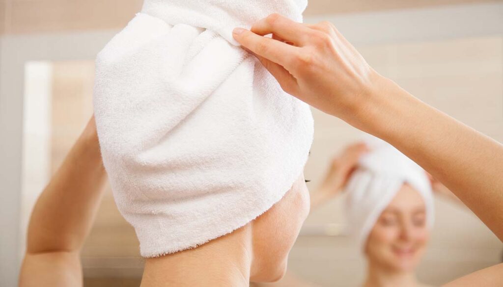 woman wrapping hair in towel after shower
