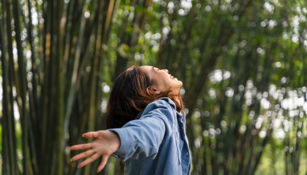 Woman with arms outstretched smiling outside