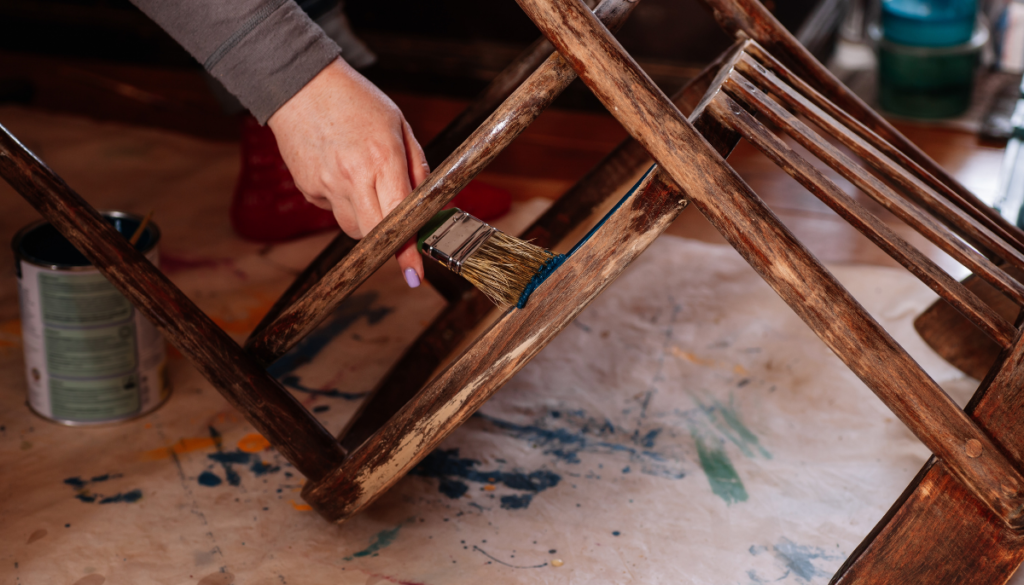 Person staining old rocking chair