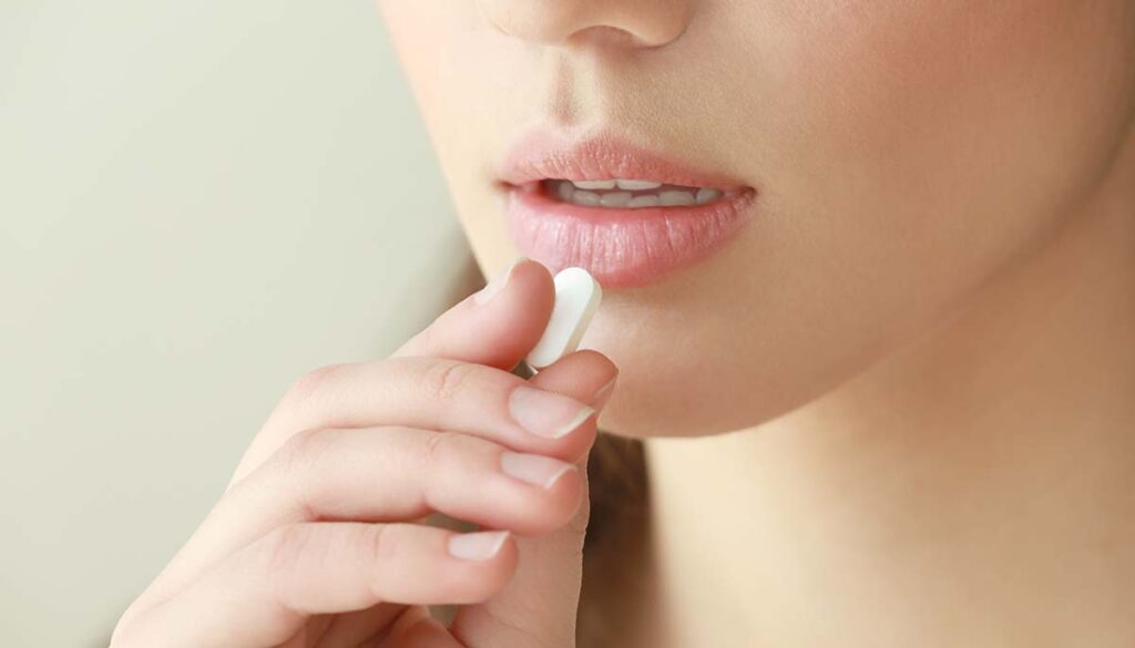 closeup of woman taking pill