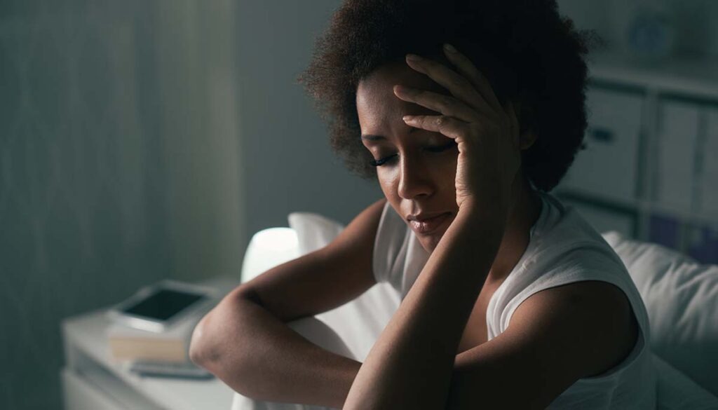 woman tired and fatigued sitting on bed