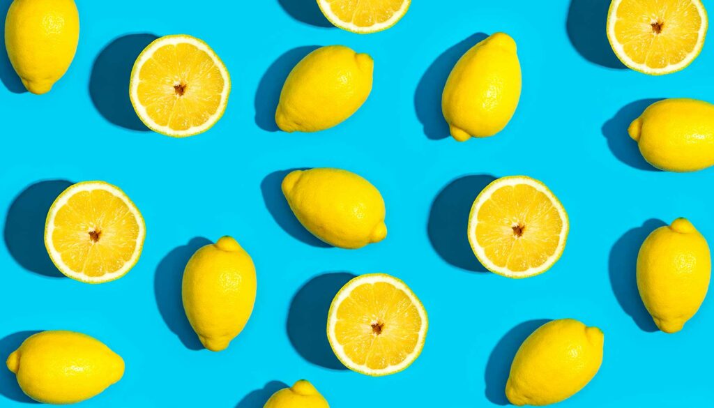 sliced and whole lemons against a blue background