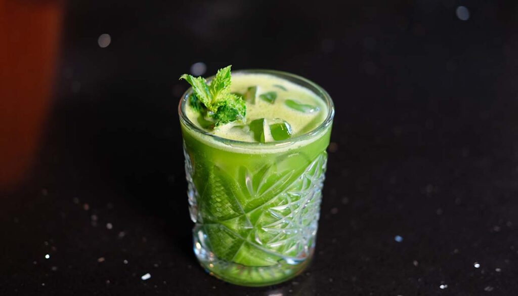 matcha cocktail or tea or latte with ice and mint isolated on black background