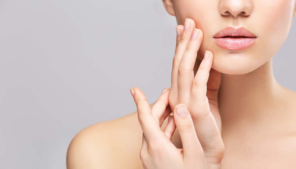 woman touching face on light gray background