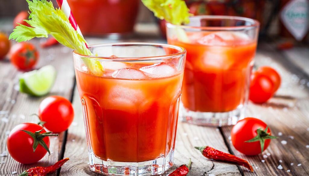 Bloody Mary with ice in glasses on a wooden table