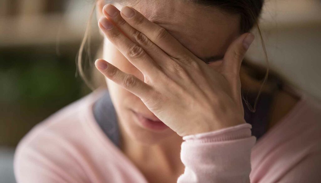 woman holding hand over face, headache concept