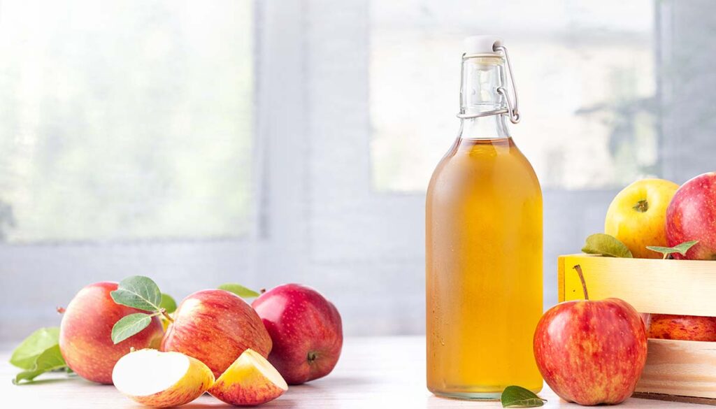picture of apple cider vinegar in glass bottle surrounded by apples