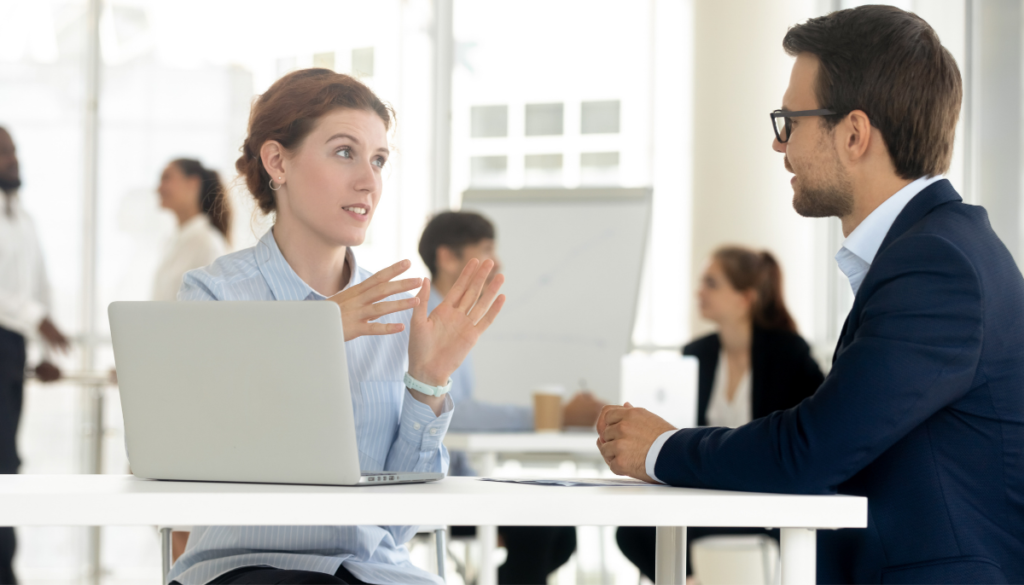 Woman employee speaking with male employee in office environment