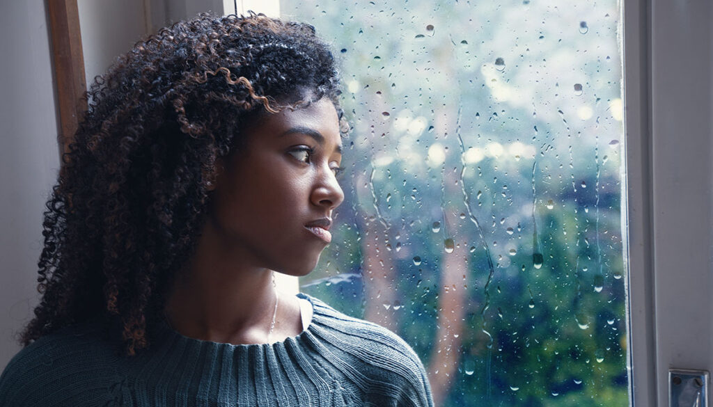 Woman looking out a rainy window