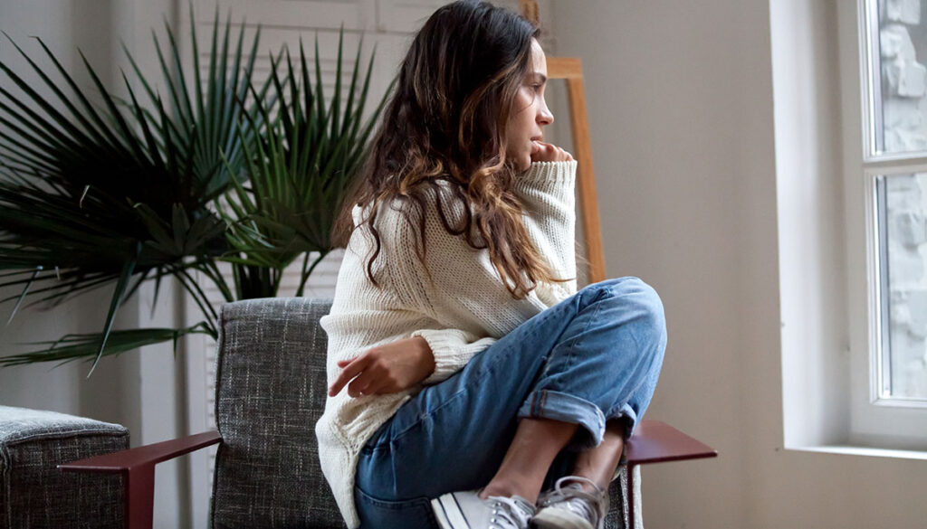 Teenager curled up in a chair looking pensive