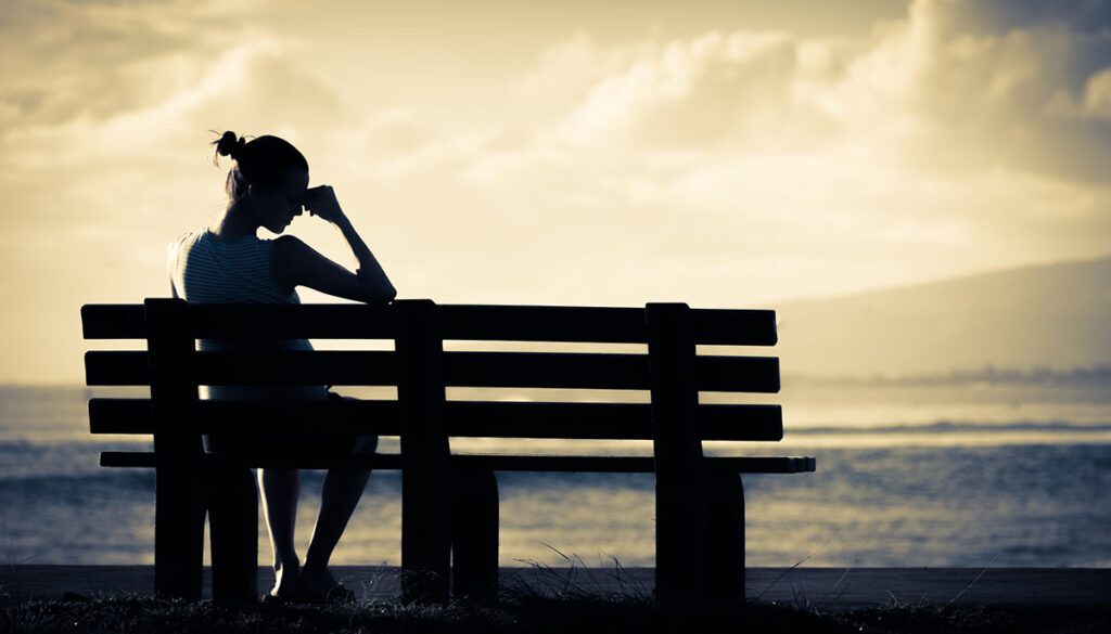 Silhouette of a woman alone on a bench