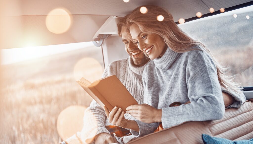 man and woman smile while reading a book