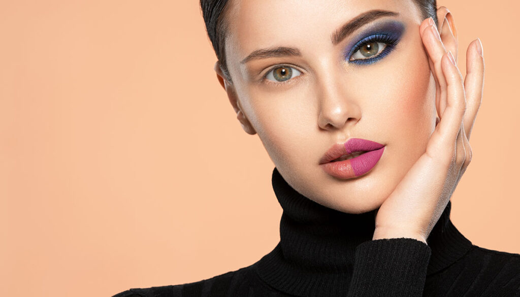 One half face of a beautiful white woman with bright makeup and the other is natural. Woman portrait with a deep blue eye makeup of one eye. Natural and vivid make-up on a female face. Fashion style