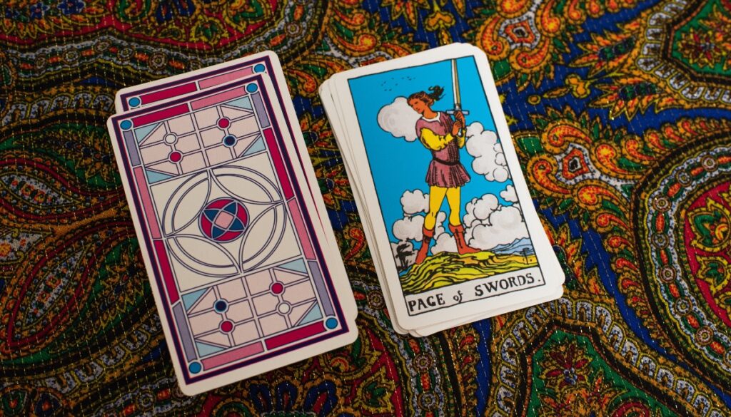 the page of swords next to a deck of cards