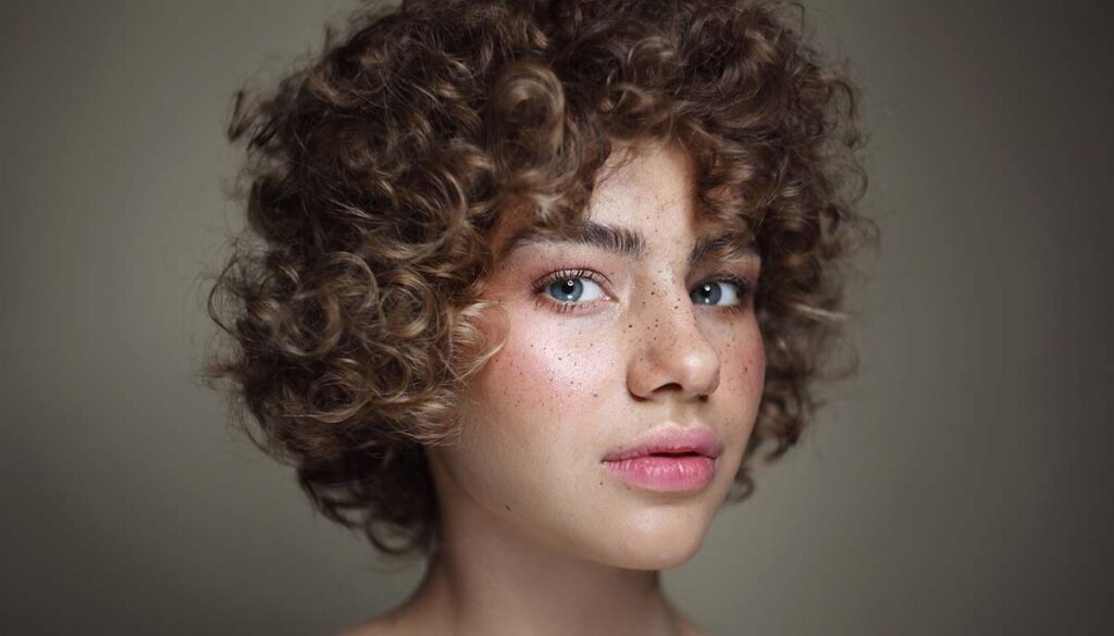 freckled girl with curly hair and clean makeup, selective focus