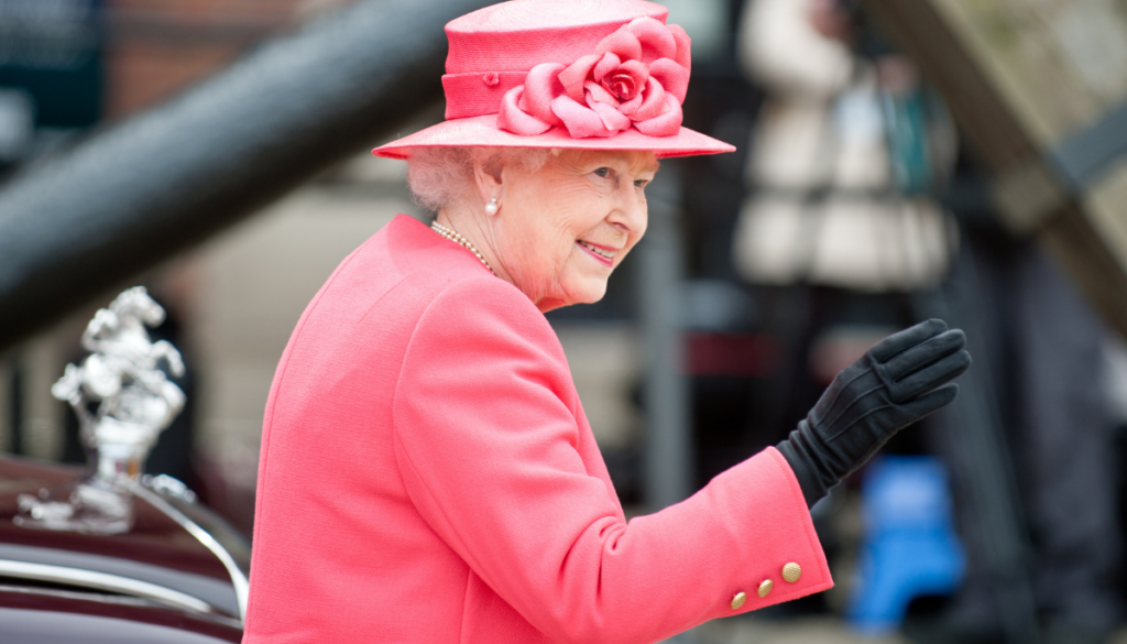 Queen Elizabeth II in a pink outfit waving