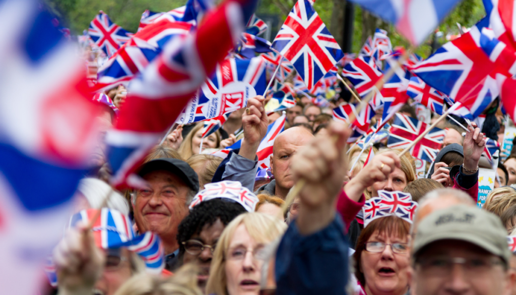 Crowd of people waving small British flags
