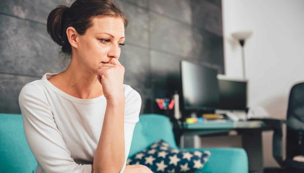 sad woman thinking, sitting on sofa