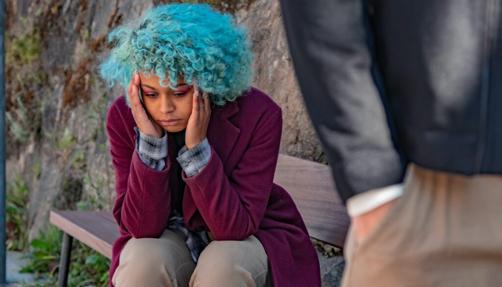 distraught blue haired person sitting down with suited person in the foreground