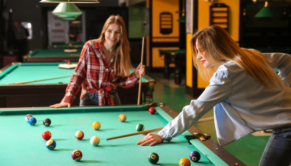 Two young women playing pool