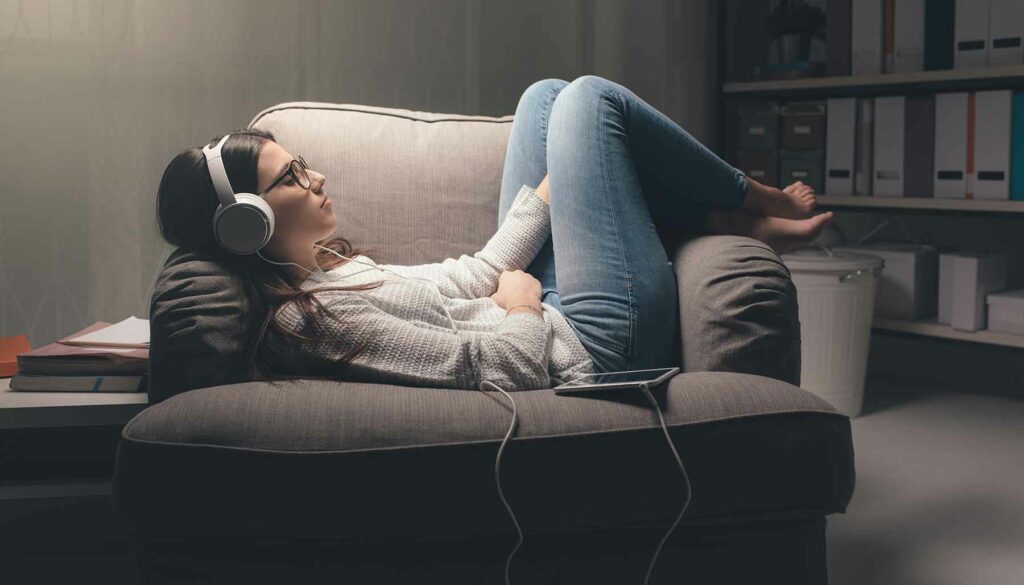 woman relaxing on chair listening to music with headphones