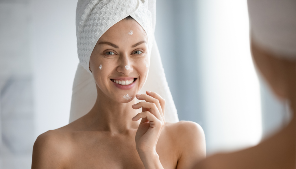 Woman with hair in towel applying sunscreen