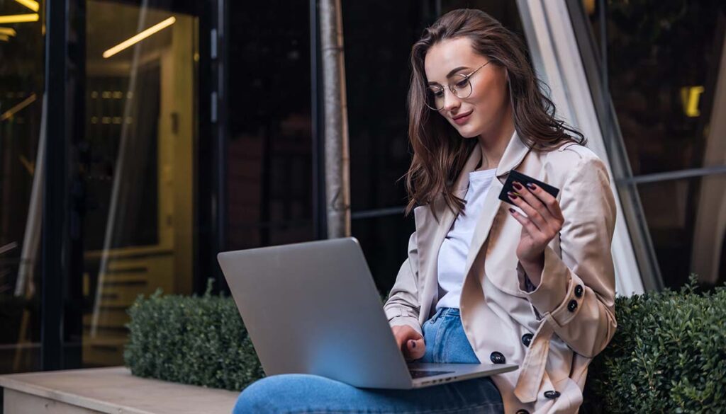 Young woman holding credit card and using laptop  to shop