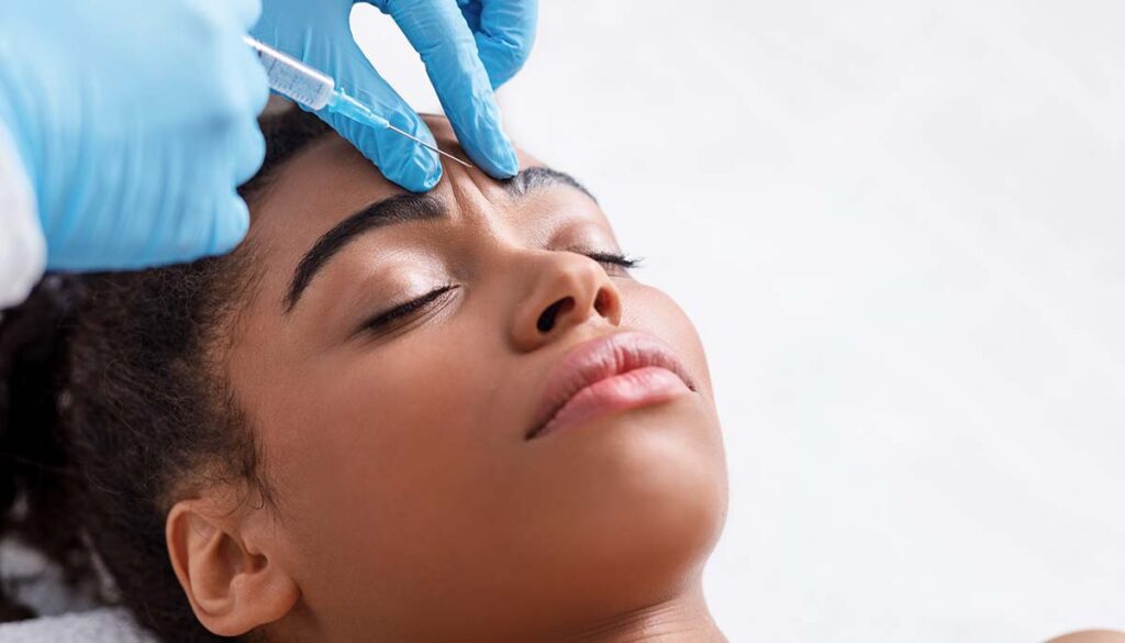 woman receiving botox injection in interbrow zone at beauty clinic