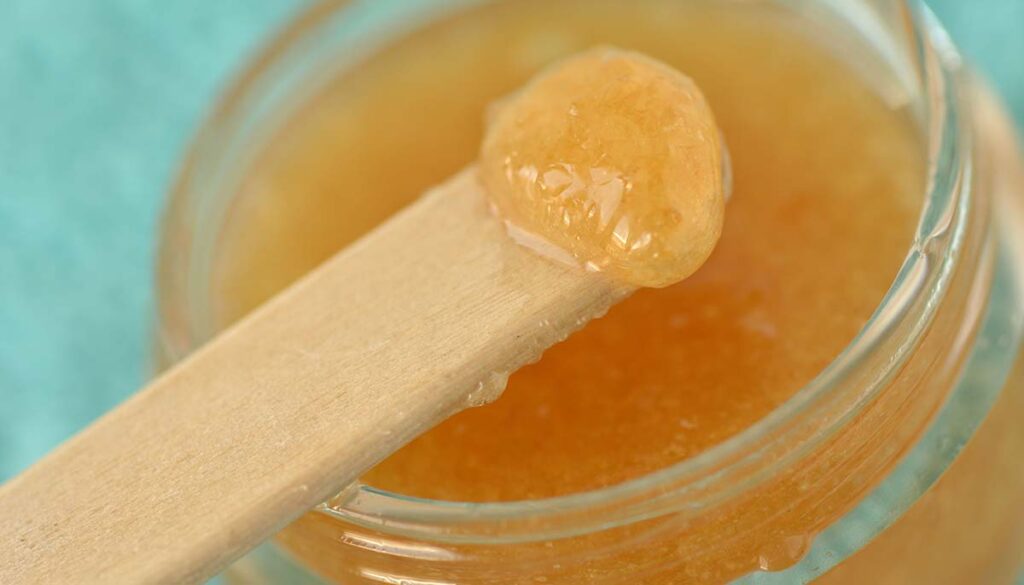 Macro of homemade lip scrub made out of brown sugar, honey and olive oil in a glass jar